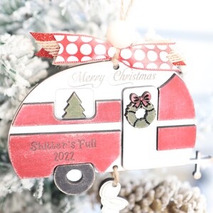 May include: Red and white wooden camper Christmas ornament with the text "Merry Christmas" and "Shitter's Full 2022".
