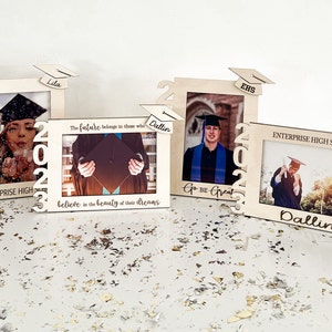 Puede incluir: Tres marcos de fotos de madera con gorros de graduación en la parte superior. Los marcos están decorados con el año 2023 y el texto "Go Be Great", "The future belongs to those who believe in the beauty of their dreams", y "Enterprise High School".