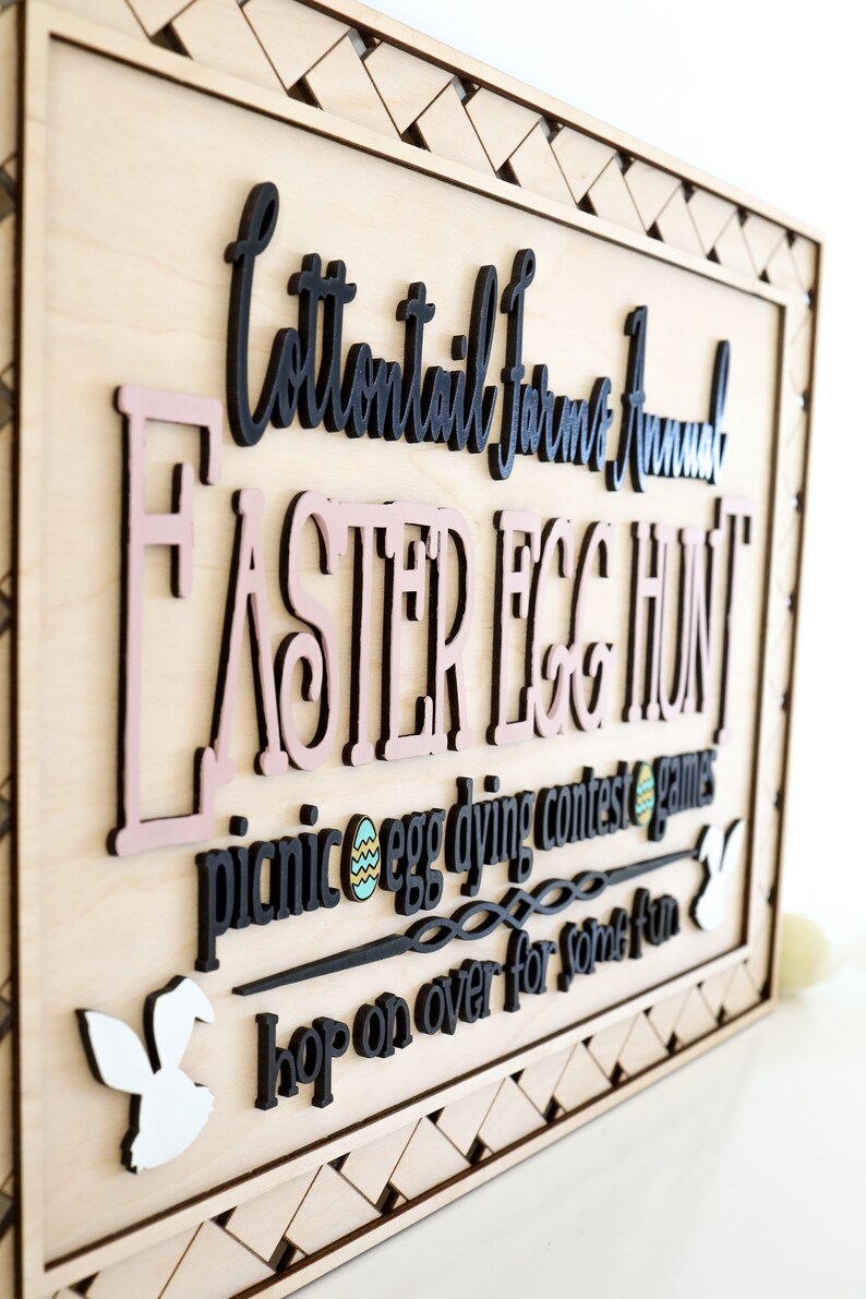 Puede incluir: Un letrero de madera con un dise&ntilde;o pintado en negro y rosa que dice "Cottontail Farm Annual Easter Egg Hunt" con las palabras "picnic, egg dying contest, games, hop on over for some fun" debajo.