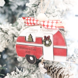 May include: Red and white wooden camper Christmas ornament with the text "Merry Christmas" and "Shifter's Full 2022".