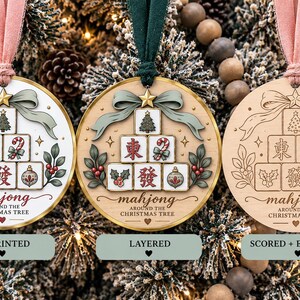 May include: Three circular ornaments with a mahjong tile design featuring a Christmas tree, candy cane, holly, and bauble. The text reads "mahjong AROUND THE CHRISTMAS TREE". One is UV printed, one is layered, and one is scored and engraved.