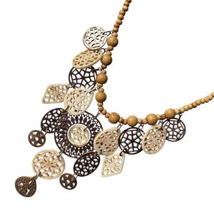 以下が含まれることがあります： 木製のビーズと精巧に彫刻されたペンダントが特徴の手作りのネックレス。 ネックレスは、茶色とクリーム色の円形、楕円形、ひし形のペンダントを組み合わせており、ボヘミアンな美学を作り出しています。