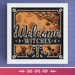 May include: A layered Halloween-themed art piece in a white frame. The design features the words "Welcome Witches" in a decorative font, with spooky silhouettes of a spiderweb, ghosts, and witch boots. The background is orange.