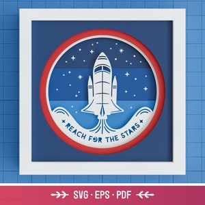 May include: A white framed image with a red circle containing a white silhouette of a rocket ship with the text "Reach for the Stars" in a blue and white wave pattern.