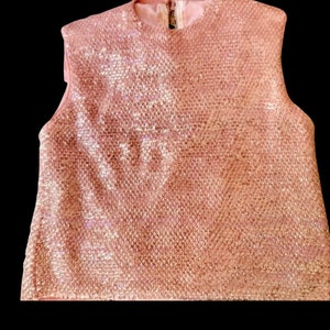 May include: A sleeveless pink sequined top with a round neckline.