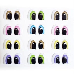 May include: A sheet of 12 pairs of plastic doll eyes. The eyes are in various colors, including brown, green, blue, pink, yellow, and purple. Each eye has a white heart shape in the center.