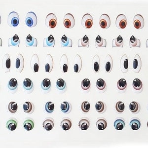 May include: A sheet of colorful plastic googly eyes in various sizes and colors, including blue, green, brown, and black. The eyes are arranged in rows on a white background.
