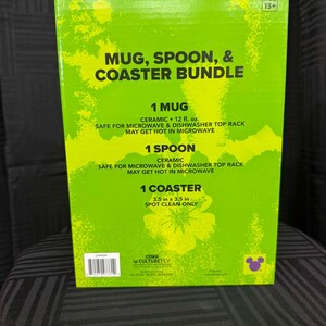 Puede incluir: Una caja verde con el texto "Mug, Spoon, & Coaster Bundle". La caja incluye una taza de cer&aacute;mica (aproximadamente 355 ml), una cuchara y un posavasos (8,9 cm x 8,9 cm). La taza y la cuchara son aptas para microondas y lavavajillas.