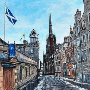 May include: An oil painting depicts a cobblestone street in Edinburgh, Scotland, with historic buildings and a church spire. A Scottish flag waves in the sky. The painting has a blue sky and snow on the street.