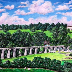 May include: A painting depicting a stone arch bridge spanning a verdant valley, with a white building visible in the distance. The sky is blue with fluffy white clouds.