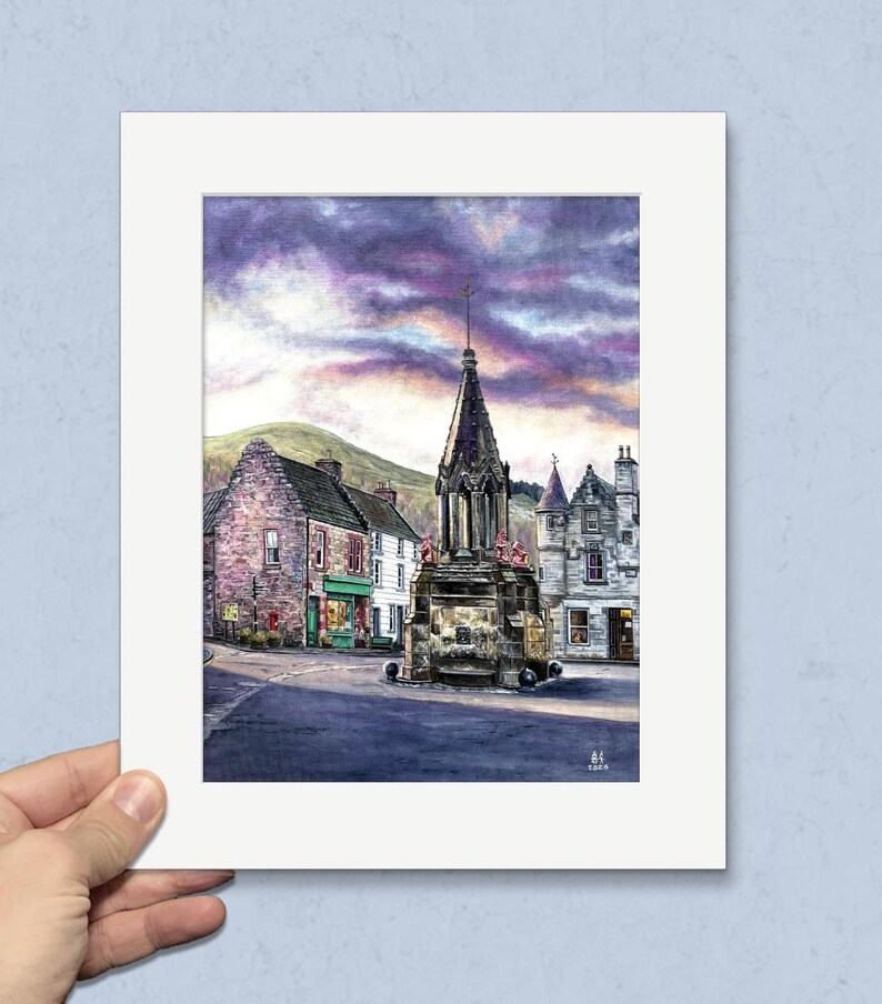 May include: Watercolour painting of a Scottish town square featuring a stone cross monument. Buildings with shops and homes surround the square. The sky is a mix of purple and grey clouds. A green hill is in the background.