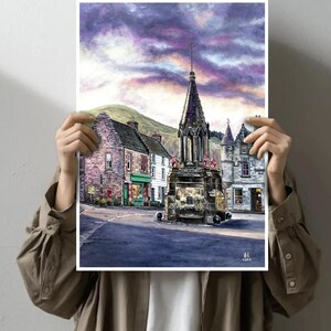 May include: Watercolour print depicting a town square with a stone monument and buildings. The sky is a blend of purple and orange. The artwork is held in front of a person.