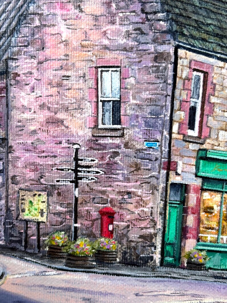 May include: A detailed acrylic painting depicting a traditional street scene. The image shows stone buildings, a red postbox, and a black signpost. Flower-filled planters sit at the base of the buildings, adding a splash of colour to the scene.