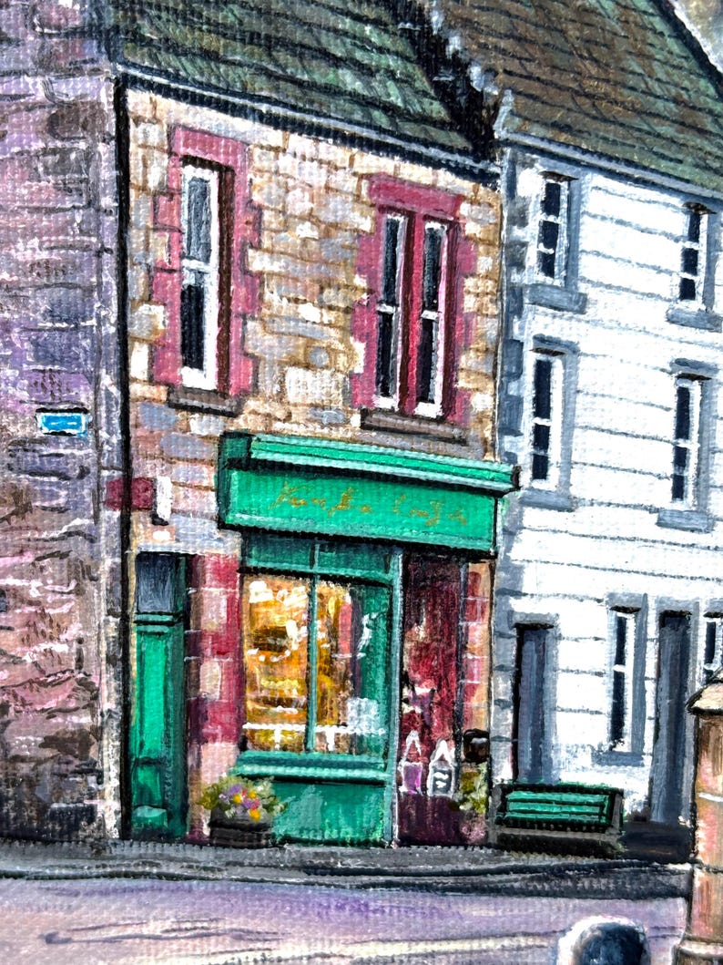 May include: A painting depicting a street scene with a shop. The shop has a green awning and door, with stone walls and red-framed windows. The shop window reveals a warm interior. A white building is next to it.