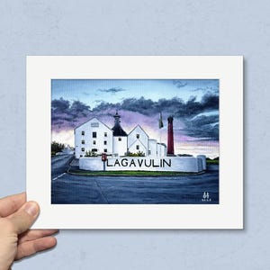 May include: A framed print of the Lagavulin distillery, featuring white buildings, a red smokestack, and the distillery's name. The artwork is set against a dramatic sky with dark clouds and a hint of sunset colors.