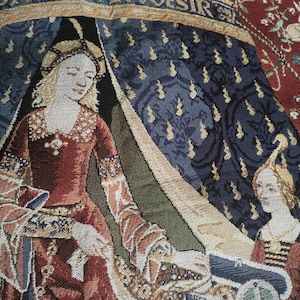 May include: A tapestry depicting a woman in a red dress sitting in a tent with the text "DON'S EVIL DESIR" above her. The tapestry has a blue and gold background with floral patterns.