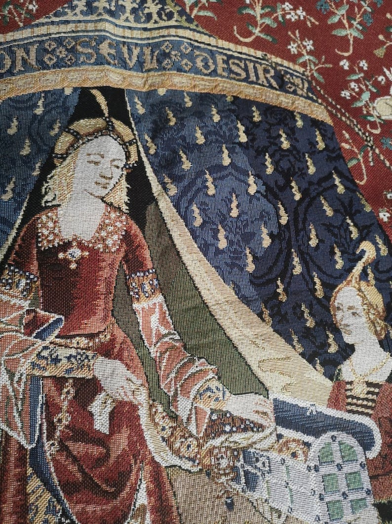 May include: A tapestry depicting a woman in a red dress sitting in a tent with the text "DON'S EVIL DESIR" above her. The tapestry has a blue and gold background with floral patterns.
