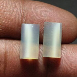 May include: Two white, rectangular, iridescent stones with a smooth, polished finish. The stones are approximately 1 inch in length and 1/2 inch in width.