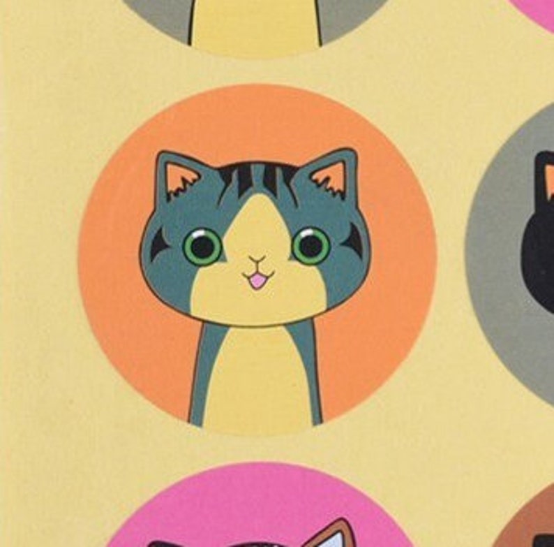 May include: A round sticker with an orange background features a cartoon cat with green eyes, a pink tongue, and gray and yellow fur.