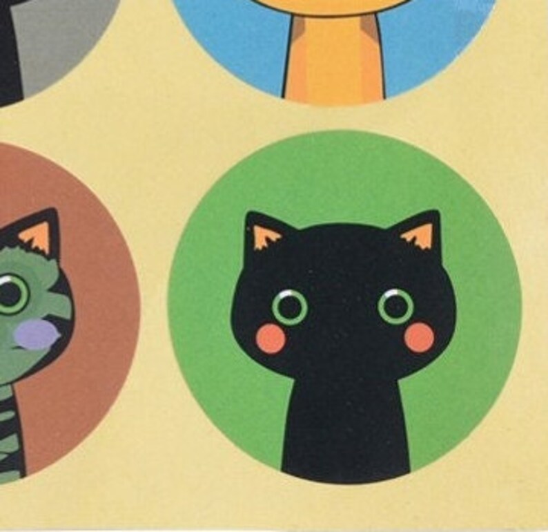 May include: A black cat with green eyes and pink cheeks is on a green circle. The cat is looking straight ahead.