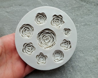 May include: White silicone mold with eight different sized rose shapes. The mold is designed for making fondant or gum paste flowers.