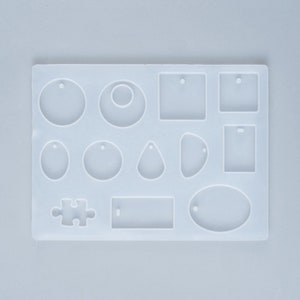 May include: A white silicone mold with various earring shapes, including circles, squares, teardrops, and a puzzle piece. Each shape has a small hole for attaching hardware. The mold is designed for crafting jewelry.