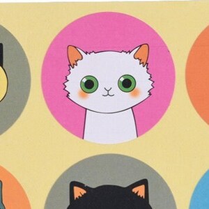 May include: A white cat with green eyes and pink cheeks is featured on a pink circle sticker. The sticker is on a yellow background.