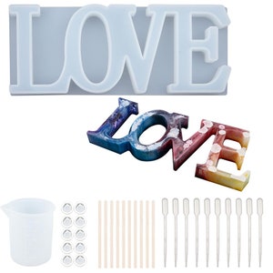 May include: A set of resin casting supplies for making a "LOVE" sign. The set includes a silicone mold, a measuring cup, droppers, wooden sticks, and clear resin. The resin is shown in the mold, creating a colorful "LOVE" sign.