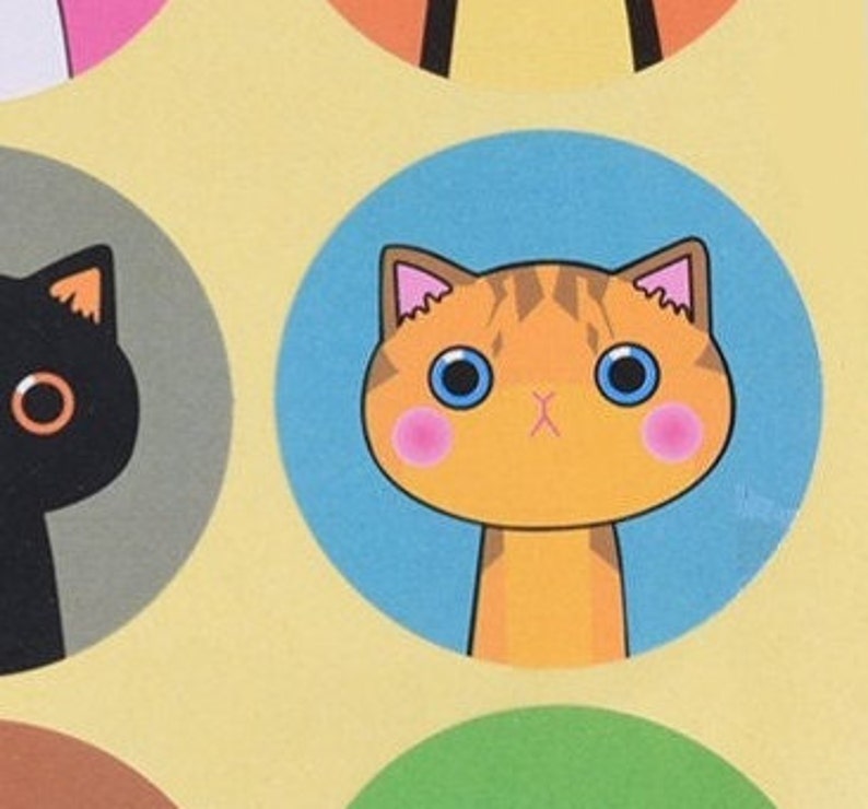 May include: A sticker featuring a cartoon orange tabby cat with blue eyes and pink cheeks. The cat is on a blue background.