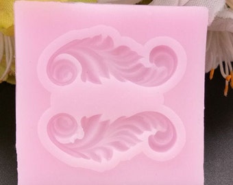 May include: Pink silicone mold with two detailed leaf designs. The mold is for making decorative cake toppers or other edible crafts.
