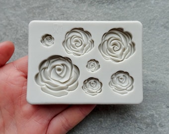 May include: White silicone mold with seven rose-shaped cavities. The mold is designed for making fondant or gum paste decorations.