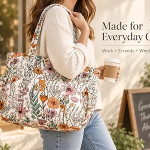 May include: A white tote bag featuring a colourful floral pattern with orange, pink, and green wildflowers. The bag has two shoulder straps and side pockets. Text on the image reads: Made for Everyday Carry, Work, Errands, Weekend.