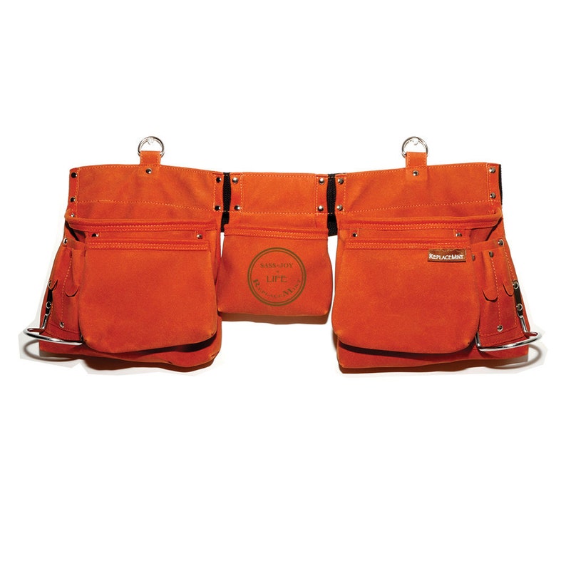 May include: Orange canvas tool belt with multiple pockets and metal hardware. The belt has a brown leather patch with the text "SASS-BOY LIFE" and another patch with the text "REPLACEMENT".
