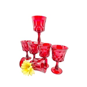 May include: Set of six red glass wine goblets with a diamond pattern. The goblets are arranged in a pyramid shape with a single goblet at the top and two goblets on each of the lower levels.