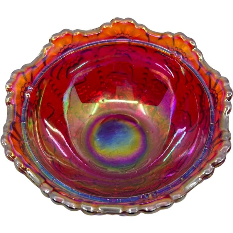 May include: A decorative iridescent glass bowl with a ruffled edge. The bowl has a vibrant red interior with hints of purple and blue iridescence. The rim is a mix of orange and silver.