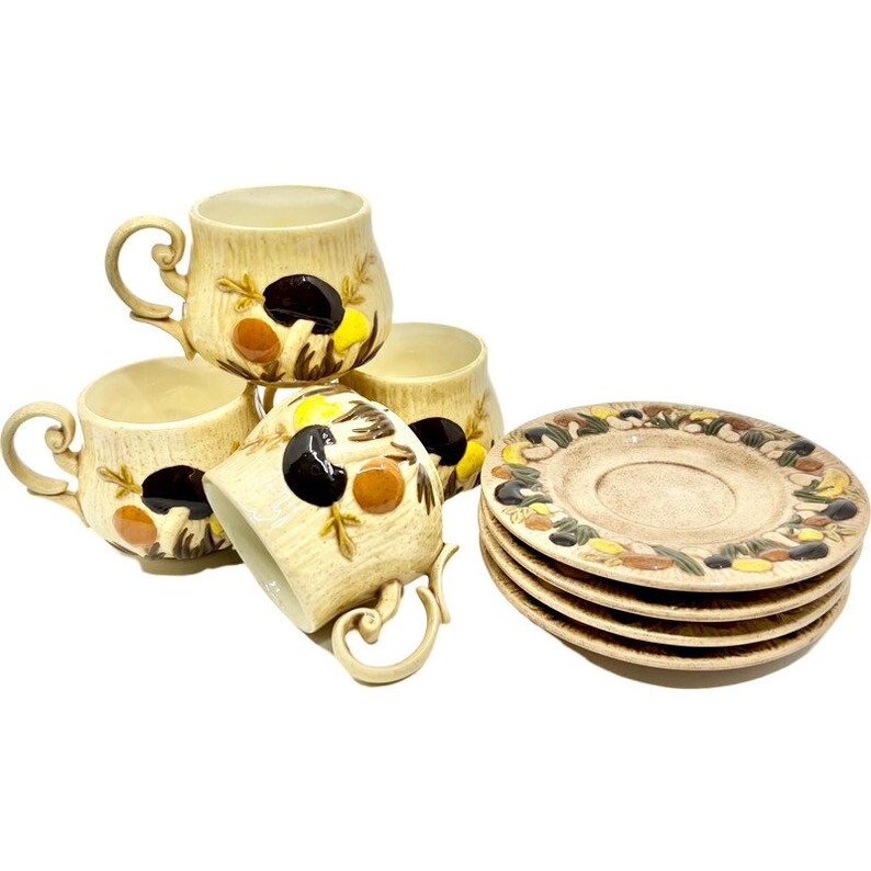 May include: Set of four ceramic teacups and saucers with a mushroom design. The cups and saucers are beige with brown, yellow, and black mushroom illustrations.