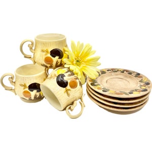 May include: Set of four vintage ceramic teacups and saucers with a mushroom design. The cups and saucers are beige with brown, orange, and yellow mushrooms.