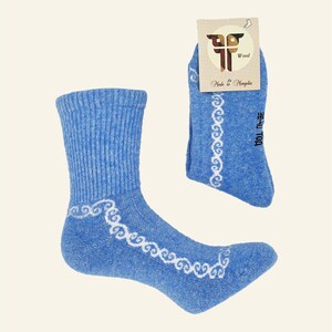 May include: A pair of blue wool socks with a white swirl pattern. The socks are made in Mongolia. The tag says "Wool Made in Mongolia".