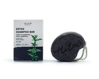 May include: A black detox shampoo bar with a string attached. The bar is labeled "Helen Detox Shampoo Bar" and "ХУЙХ ГҮН ЦЭВЭРЛЭХ ХАТУУ ШАМПУНЬ" in Mongolian. The bar is packaged in a white box with a green leaf design.