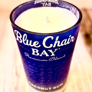 May include: A blue glass candle jar with a white candle inside. The jar has the text "Blue Chair Bay Premium Blend Coconut Rum" printed on it.