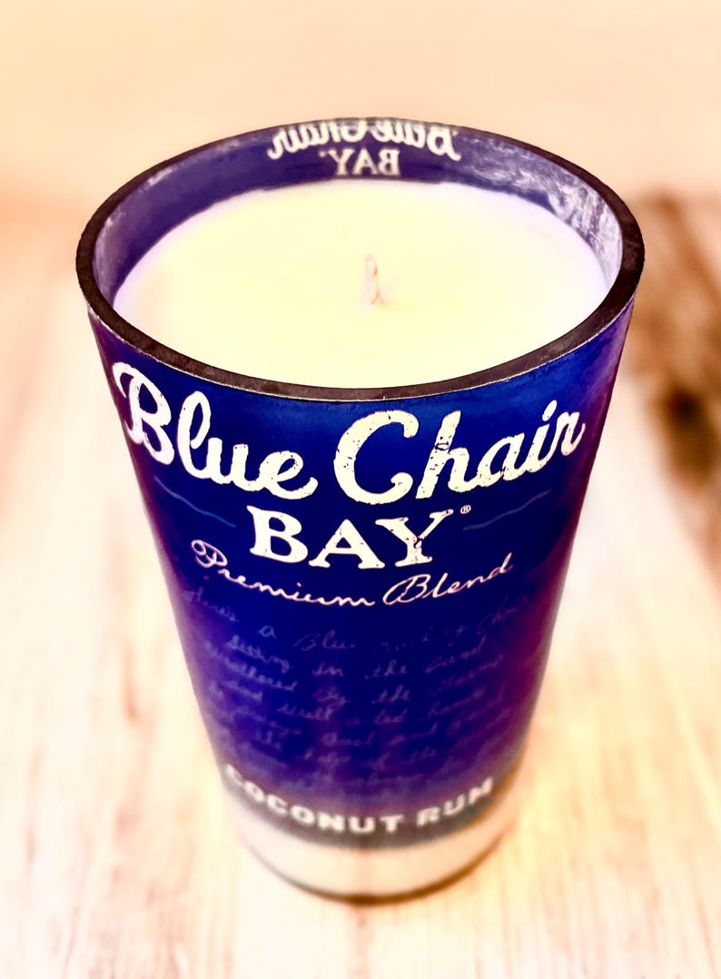 May include: A blue glass candle jar with a white candle inside. The jar has the text "Blue Chair Bay Premium Blend Coconut Rum" printed on it.