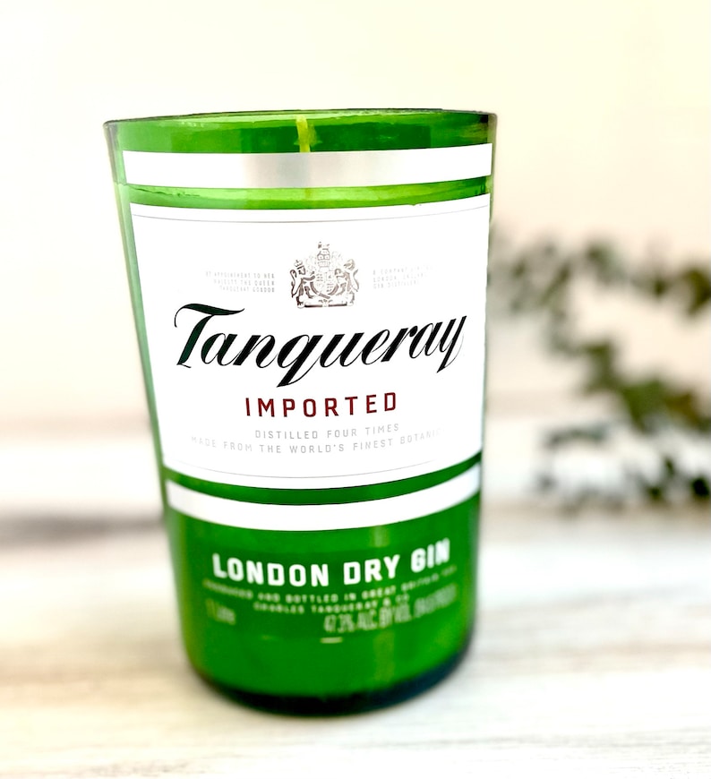 Może przedstawiać: Zielony szklany słoik na świecę z białą etykietą, na kt&oacute;rej widnieje napis "Tanqueray Importowany" i "London Dry Gin".