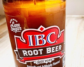 May include: A brown glass candle in the shape of an IBC Root Beer bottle. The label features the IBC logo in red and white, with text that reads "Root Beer" and "Since 1919". The candle is 12 fl oz (355 mL).