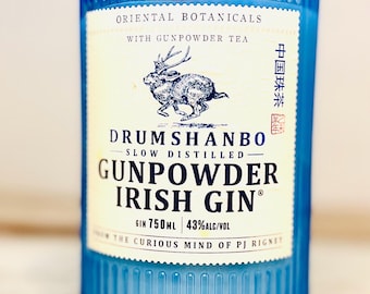 May include: A blue glass bottle of Drumshanbo Gunpowder Irish Gin. The label features a drawing of a hare and text that reads "Oriental Botanicals with Gunpowder Tea." The bottle contains 750ml of gin, 43% alcohol by volume.