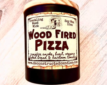 May include: A black candle jar with a wooden lid. The label reads "Wood Fired Pizza" with the text "Soy Wax 10oz" and "Crackling Wood Wick". The label also includes the text "campfire smoke, basil, oregano, baked bread & heirloom tomato" and "www.deconstructedcandles.com".