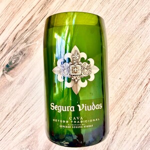 May include: A green glass bottle with a gold label that reads "Segura Viudas Cava Metodo Tradicional Elaborado en Heredad Segura Viudas".