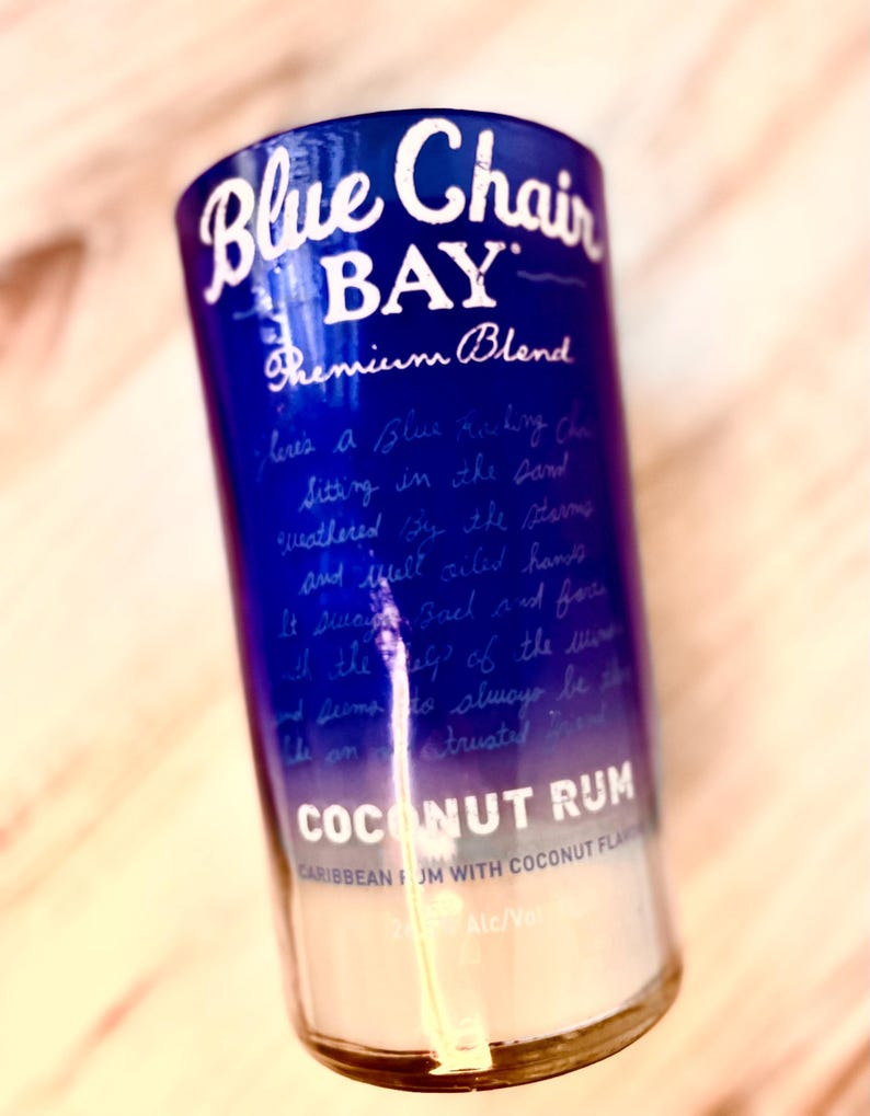 May include: A glass bottle with a blue and white label that reads "Blue Chair Bay Premium Blend Coconut Rum Caribbean Rum with Coconut Flavor 2% Alc/Vol".