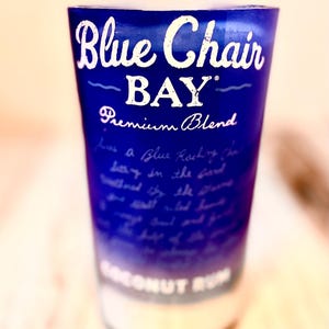 May include: A blue glass bottle with a white label that reads "Blue Chair BAY" Premium Blend. The bottle is filled with a clear liquid and has a white cap.