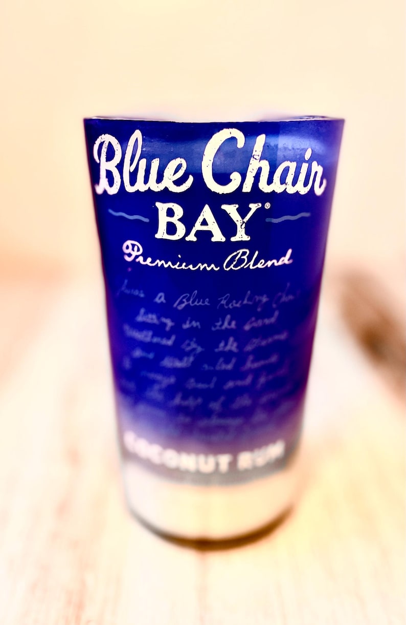 May include: A blue glass bottle with a white label that reads "Blue Chair BAY" Premium Blend. The bottle is filled with a clear liquid and has a white cap.