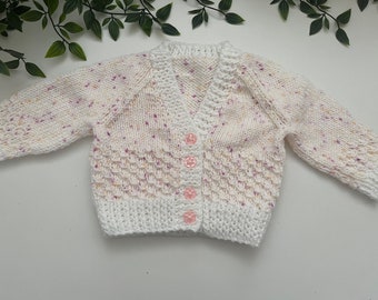 Baby’s white hand knitted cardigan with purple and peach speckles. Personalise with name embroidered onto the back. Roughly fit 0/3 months